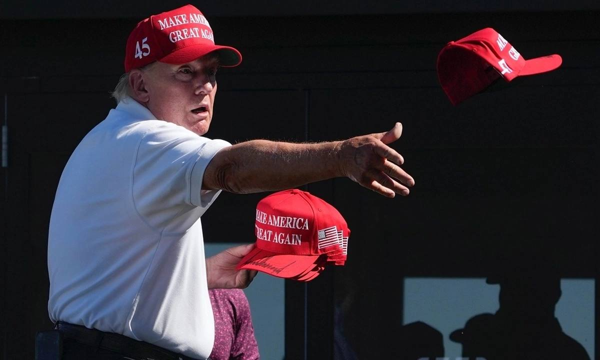 Donald Trump tossing red MAGA hats to a crowd